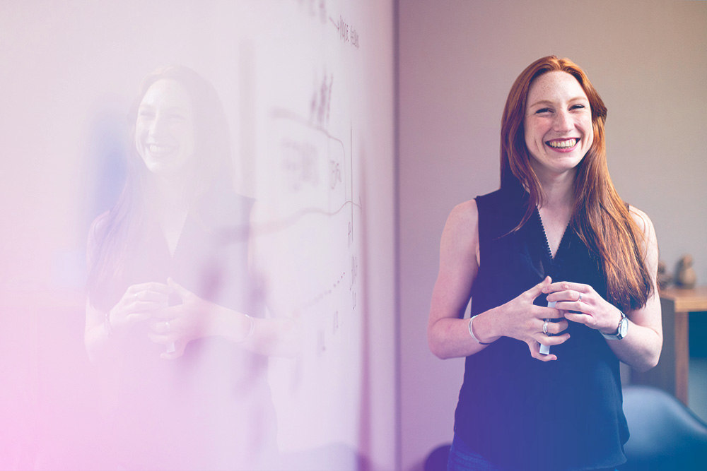 Happy woman speaking in front of a whiteboard